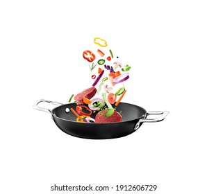 Nonstick frying pan with falling beef slices and vegetables on white background. Process of cooking.
