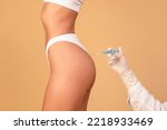 Non-sugical butt lifting sculptra concept. Side view of young woman getting hip injection at buttocks area, isolated on beige studio background, cropped