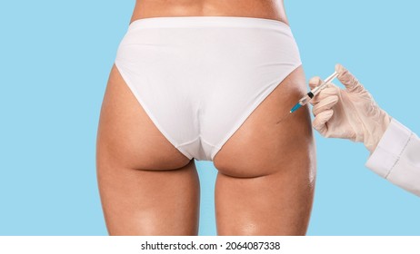 Non-Sugical Butt Lifting Sculptra Concept. Rear back view of young lady getting hip injection at beauty salon, closeup cropped. Surgeon making injection at buttocks area, isolated on studio background