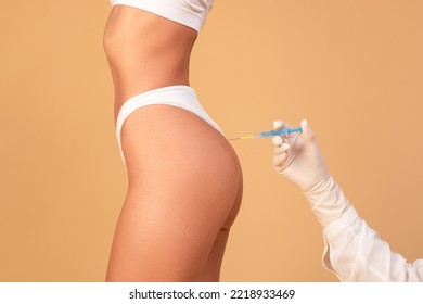 Non-sugical butt lifting sculptra concept. Side view of young woman getting hip injection at buttocks area, isolated on beige studio background, cropped