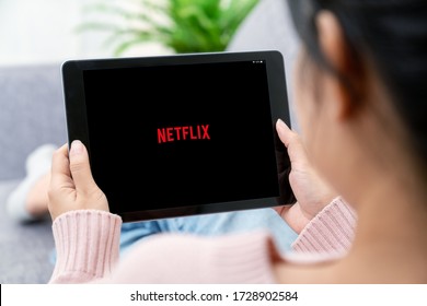 NONTHABURI ,THAILAND - APRIL 15, 2020 : Woman using mobile tablet watching Netflix on application on sofa. Netflix is a global provider of streaming movies and TV series. Next or new normal life.