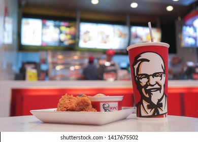 Nonthaburi, Thailand - April 22, 2018 : Cup of KFC's Cola with hot Chicken fried and Mashed potato in the background of KFC (Kentucky Fried Chicken)restaurant.