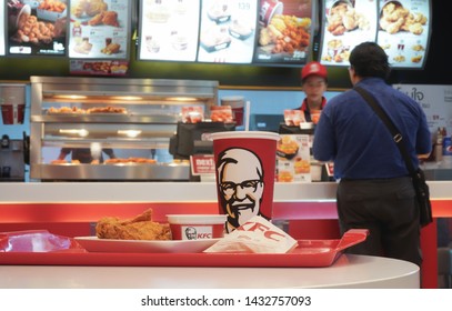 Nonthaburi, Thailand - February 23, 2019 : Cup of KFC's Cola with hot Chicken fried, french fries and Mashed potato in the background of KFC (Kentucky Fried Chicken)restaurant.