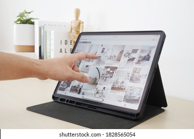 NONTHABURI, THAILAND - OCTOBER 7, 2020 : A Man's Hand Points To A Picture From Pinterest On The Ipad Screen To Find Ideas For Decorating His Home.