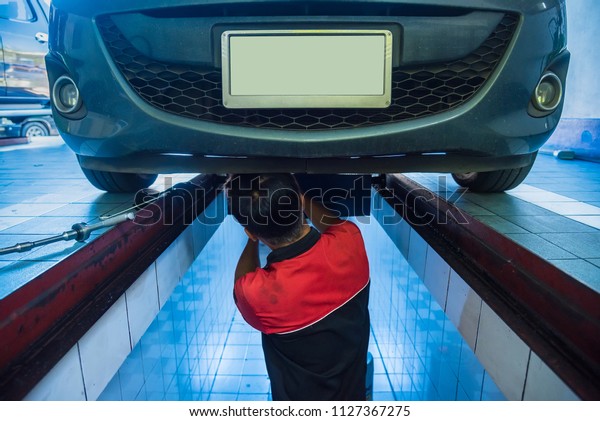 Nonthaburi,Thailand-July, 04, 2018:Unidentified\
name Profecional mechanic working under car draining engine oil\
from a car for an oil change at maintenance repair service station,\
Nonthaburi,\
Thailand