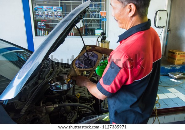 Nonthaburi,Thailand-July, 04, 2018:Unidentified\
name Profecional mechanic working change oil car engine, Filling\
the engine oil into car at maintenance repair service station,\
Nonthaburi,\
Thailand