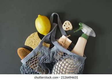 non-toxic home cleaning products in a knitted mesh bag, lemon, soda, spray bottle and cleaning tool on a dark green background, eco cleaning concept copy space top view - Powered by Shutterstock