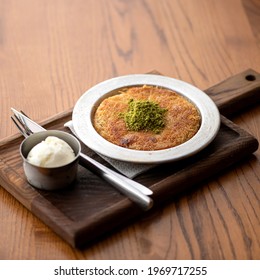 Noodle casserole. Hot baked spaghetti with cheese and a scoop of ice cream on wooden cutboard at table. Food concept. Square format or 1x1. Soft focus.