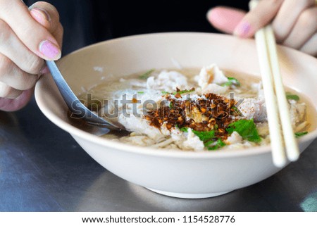 Noodle with hand of woman holding spoon and chopsticks.Selective focus