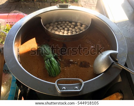 Noodles soup and meat balls in stainless steel pot under morning sunshine