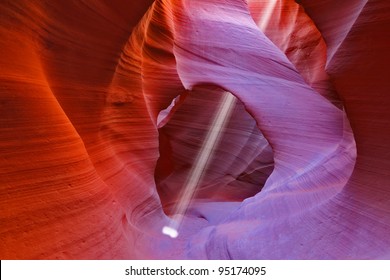 Noon In A Red-orange Antelope Canyon. A Thin Ray Of Sunlight Illuminates The Sandy Bottom Of The Canyon