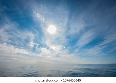 Noon Sun Shining Through Cirrus Clouds Over The Open Calm Ocean.