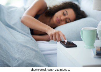 Nope, Im Ignoring You Mr Alarm. Shot Of An Attractive Young Woman Laying In Bed During The Morning And Pressing Snooze On Her Phone.