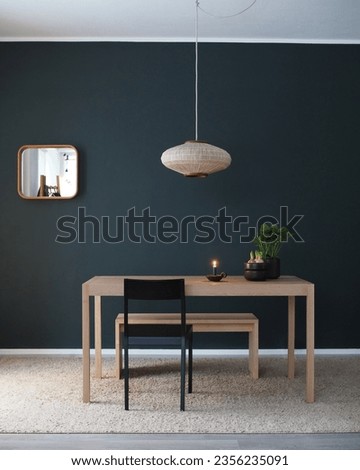 Nordic minimalist interior with dark green wall and vintage pendant light. Christmas season flowers (hyacinth, skimmia) and a candle on a table.