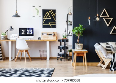 Nordic Natural Interior In Stylish Open Studio For A Freelancer With Sofa, Black Wall And Office Space With Desk And Black Accent