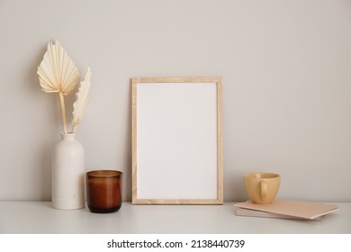 Nordic Style Home Office Desk In Living Room. Picture Frame Mockup, Candle, Dry Flowers In Vase, Cup Of Tea, Paper Notebook On White Table.