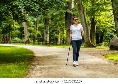 Nordic walking - middle-aged woman working out in city park - Shutterstock ID 1175831137
