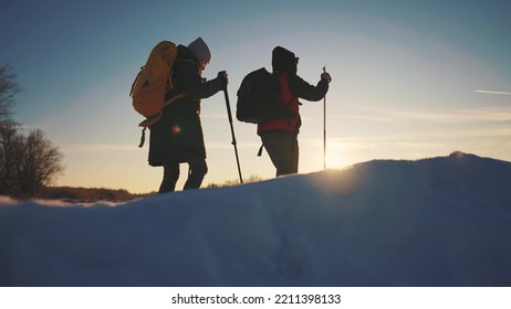 Nordic Walking In Winter. Winter Hike Group Of Tourists Silhouette. Teamwork Travel. Two Hikers With Sticks Walk In The Winter In The Snow At Silhouette. Activities Sunset In Winter Happy Family