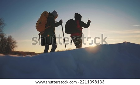 nordic walking in winter. winter hike group of tourists silhouette. teamwork travel. two hikers with sticks walk in the winter in the snow at silhouette. activities sunset in winter happy family