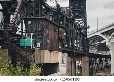 The Norfolk Southern Cuyahoga River Bridge with the George V. Voinovich Bridge in the background. It is an old, rusted metal bridge made of iron and steel framework. It raises and lowers for ships.