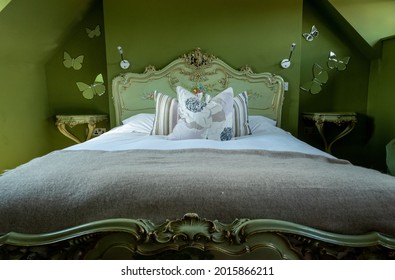 Norfolk UK. July 2021. Eclectic Bedroom With French Rococo Style Bed, And Walls Painted In Deep Green Colour