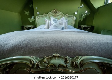 Norfolk UK. July 2021. Eclectic Bedroom With French Rococo Style Bed, And Walls Painted In Deep Green Colour.