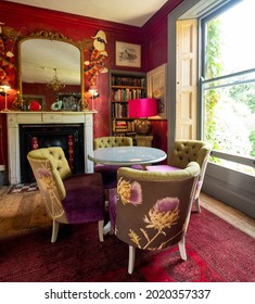Norfolk uk. July 2021. Eclectic living room with brightly coloured velvet upholstered chairs and other items of colourful furniture and objects.