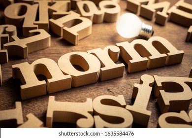 NORM word by wood alphabets with many random letters around and glowing light bulb