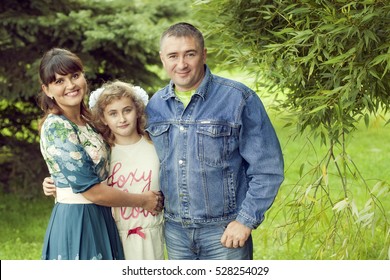 A Normal Happy Family Posing In The Park Mom, Dad And Daughter 10 Years Fun Walk In The Summer Park
