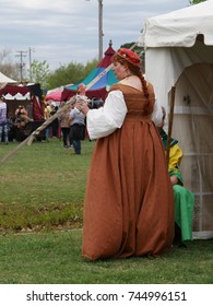 NORMAN, OKLAHOMA—APRIL 2017: A Woman In A Brown Medieval Costume Holds A Huge Turkey Leg Outside A Tent At The Medieval Festival Grounds In Norman.