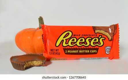 Norman, OK Oct. 31, 2018 Reese's Peanut Butter Cup Candy In Front Of An Orange Pumpkin With A White Background 