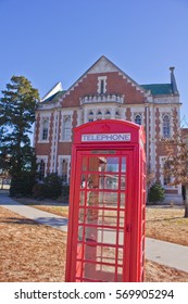 NORMAN, OKLAHOMA - DECEMBER 16, 2013: A Classic Red, British Style Telephone Booth Stands Ready On An American University Campus.