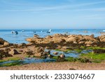 Normandy, France. Beautiful beach with boulders in Cotentin Peninsula (or Cherbourg Peninsula) at Vicq-sur-Mer. Fishing and sailing boats mooring in bay calm water. Eco tourism background.