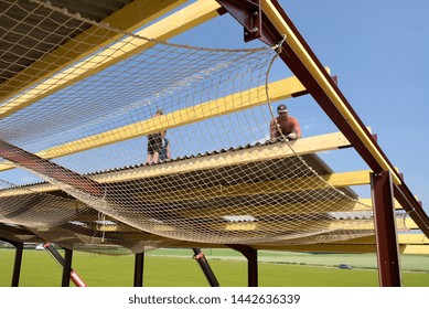 Normandy, France, March 2008.
Construction Of A New Farm Building For Cows Breeding With A Steel Frame. Roof Sheathing Installation. Roofer On The Roof. Installation Of Safety Net As Fall Prevention