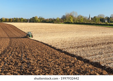 Normandy, France, November 2005. Autumn Plowing On A Cornfield. Winter Wheat Planting With Simultaneous Soil Tillage. Church In The Background