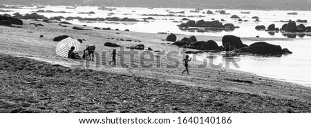 Normandy, France. Silhouettes (unrecognizable) of grandparents with three little grandchildren at beach. Summer family seaside vacation. Happy childhood, happy together concept. Black white photo.