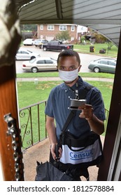 Norristown, PA/USA-August 5, 2020:  Young, Handsome Census Taker Door Knocker Stands In The Doorway Of A Home With The Door Open, Showing His Badge.  He Wears A White Mask.