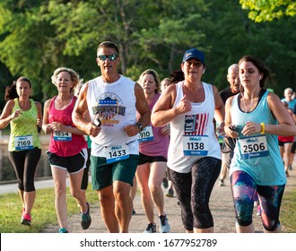 North Babylon, New York, USA - 8 July 2019: close up of many runners racing a 5K around Belmont Lake State Park during the annual State Park summer series races.