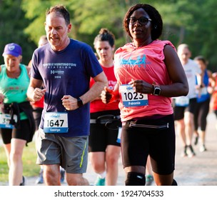 North Babylon, New York, USA - 8 July 2019: Close up of adult runners racing a 5K around Belmont Lake in the early evening in the summer.