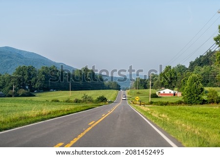North Carolina highway road with blue sky near Blue Ridge Mountains parkway with countryside rural country scenery in Marion, McDowell County on US-221 and green farm fields, houses in summer
