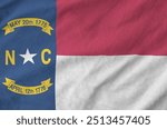 North Carolina US state flag depicted on folded wavy fabric of old cloth close up