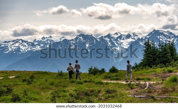 North Cascades National Park - Washington - United\
States - July 23rd 2021.  Three hikers walk a trail along Sunrise\
Point at North Cascades National Park with the Cascade Range in the\
background. 