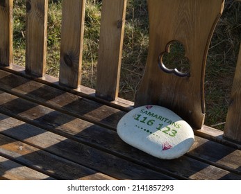 NORTH DEVON, ENGLAND - MARCH 5 2022: Stone Left On Bench, With Samaritans Phone Number. Mental Health, Suicide Issues.