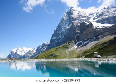 The north face of the Eiger, with the Wetterhorn in the background, reflected in the reservoir, also showing the museum of the Eiger North Face.