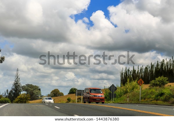 North Island, New\
Zealand - December 29, 2018:  Cars driving on a wide road on the\
countryside of New\
Zealand.