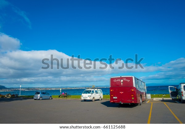 NORTH ISLAND, NEW ZEALAND- MAY 18, 2017: Some cars\
parked in the street, and beautiful view of Lake Taupo with\
mountains in the background at spring, North Island of New Zealand\
with beautiful blue