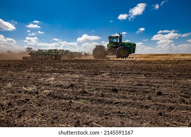 North Kazakhstan Province, Kazakhstan - May 12, 2012: Spring sowing campaign. John Deere tractors cultivating soil with harrow.Blue sky, clouds - Shutterstock ID 2145591167
