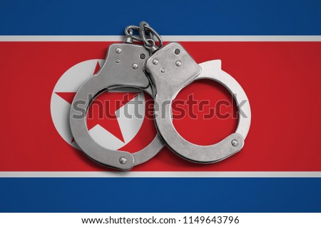 North Korea flag  and police handcuffs. The concept of observance of the law in the country and protection from crime