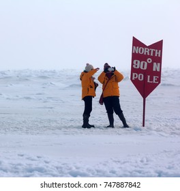 North Pole - 15 July 2016: Best Arctic Journey. Entertainment Tourists. Pointer Of Geographical North Pole Poit Where All Longitude And 90 Degrees Latitude. American Tourists Takes Picture 