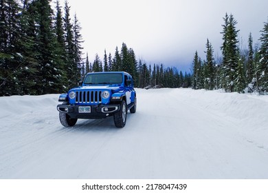 North Pole, Alaska, USA - 02-25-2022: Blue Jeep Wrangler Unlimited 4x4 Off-Road Winter Adventure Snowy Alaskan Backcountry Trail Through A Dense Evergreen Forest With A Thick White Clouded Arctic Sky